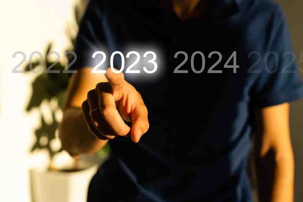 Finger pressing blue start 2023 button on virtual interface on gray background with copy space for text. Concept of new year. Businessman pressing 2023 start up business. Beginning of New Year 2023.