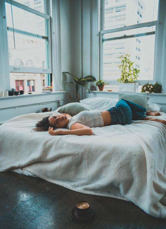 woman laying on her bed with coffee