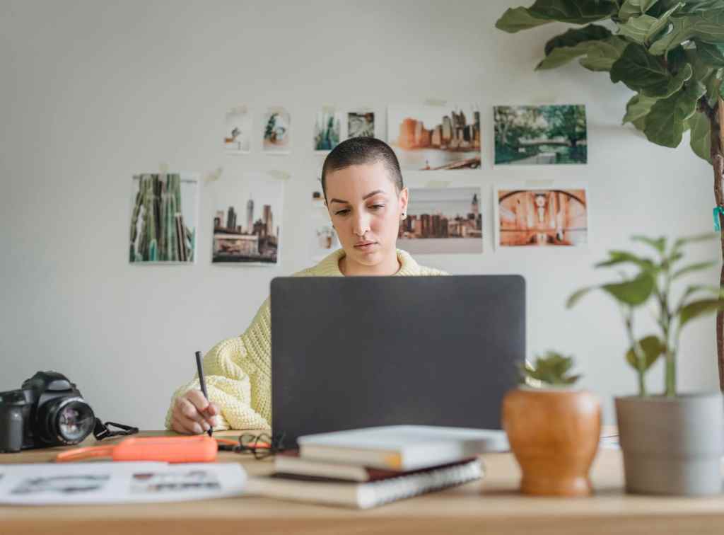 female artist working at desk with laptop, camera, photographer